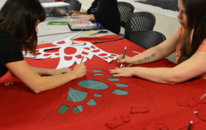 Indigenous youth making a button blanket in Urban Native Youth Association's Overly Creative Minds studio.