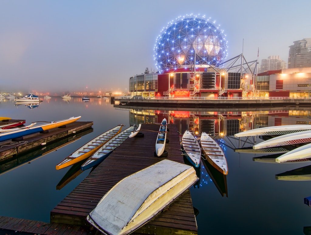 Boats docked in False Creek with Science World in the background.